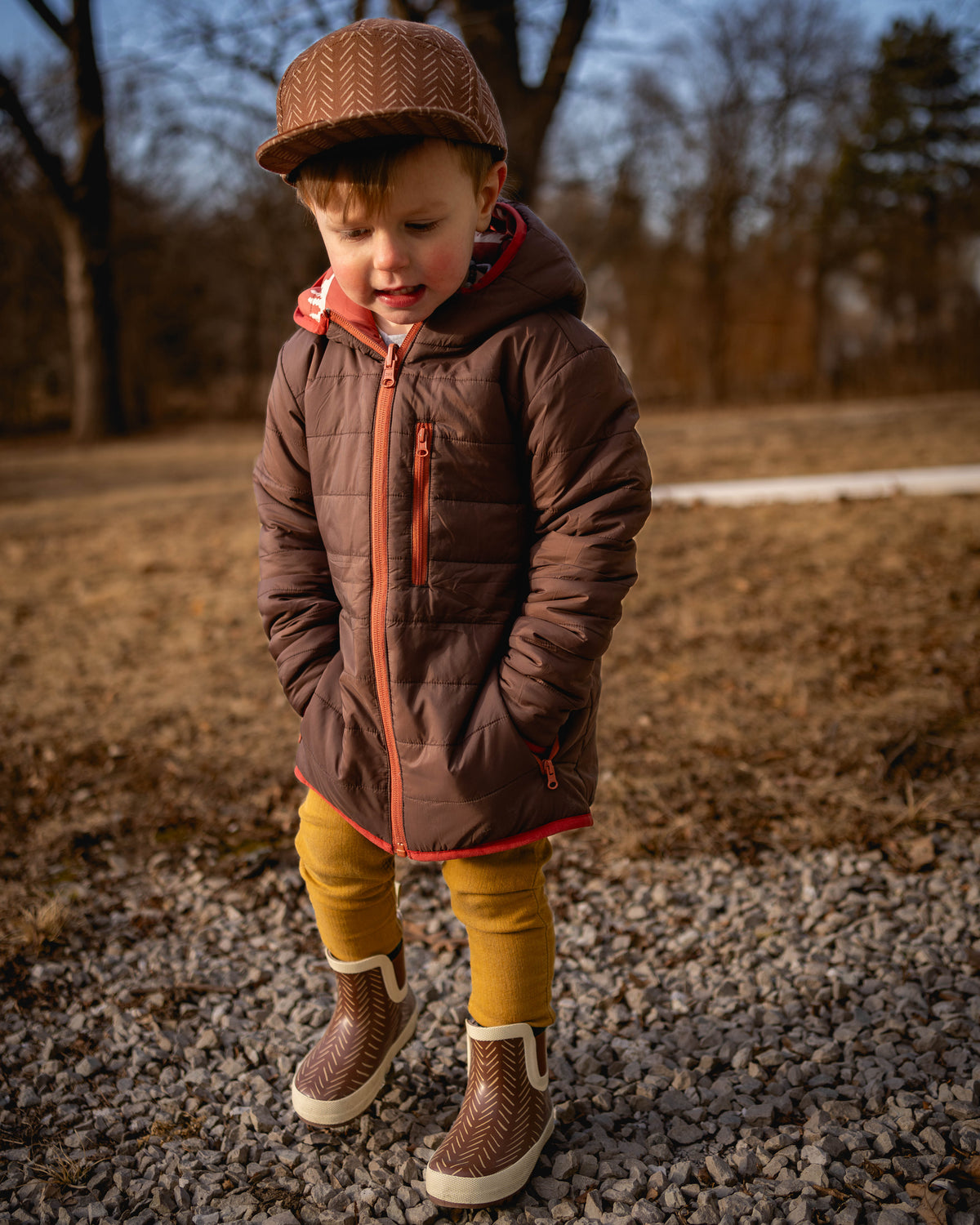 Kids reversible puffy jacket with brown hood, orange zipper trim, and quilted body