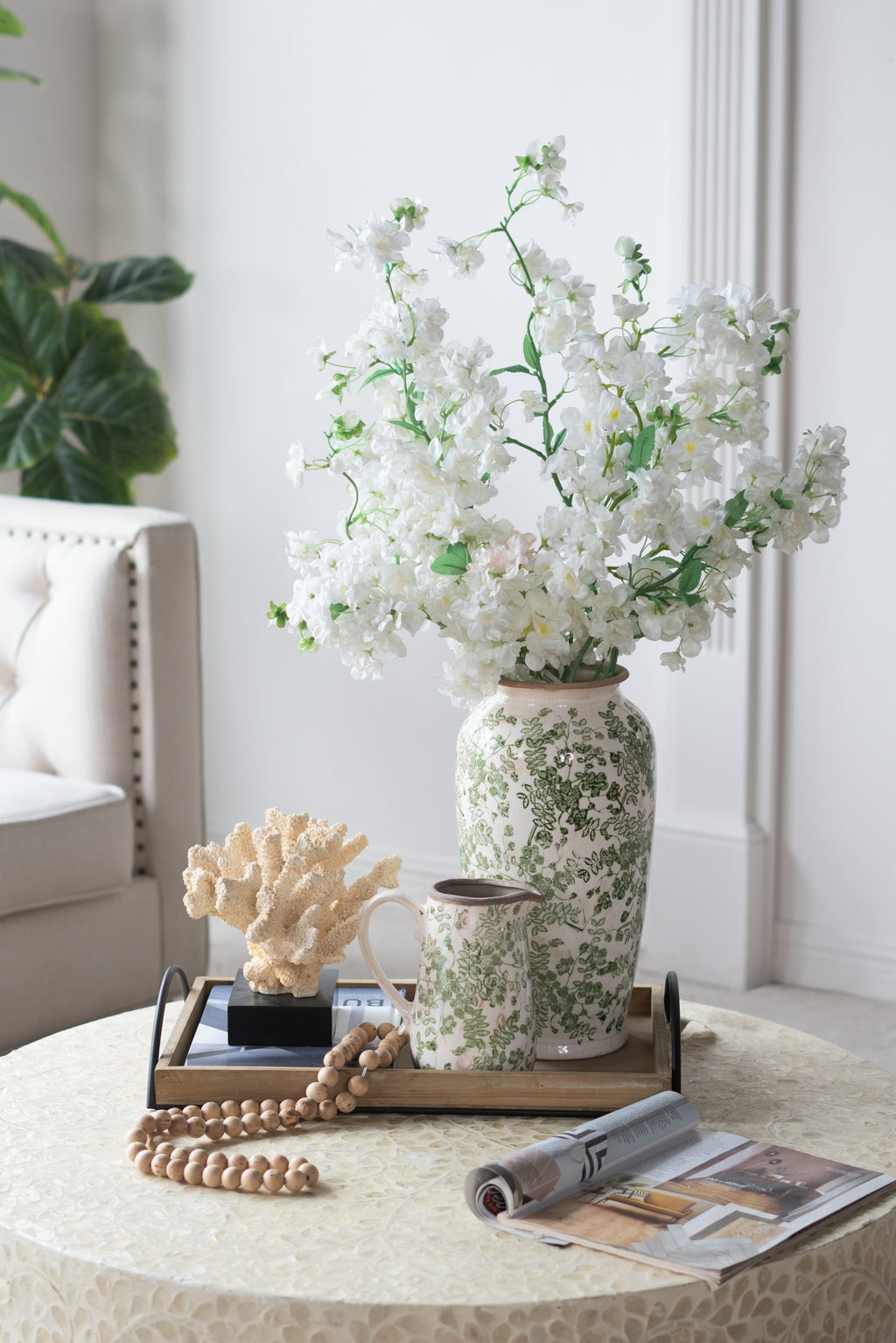 White ceramic flower vase with green floral pattern holding white blooms