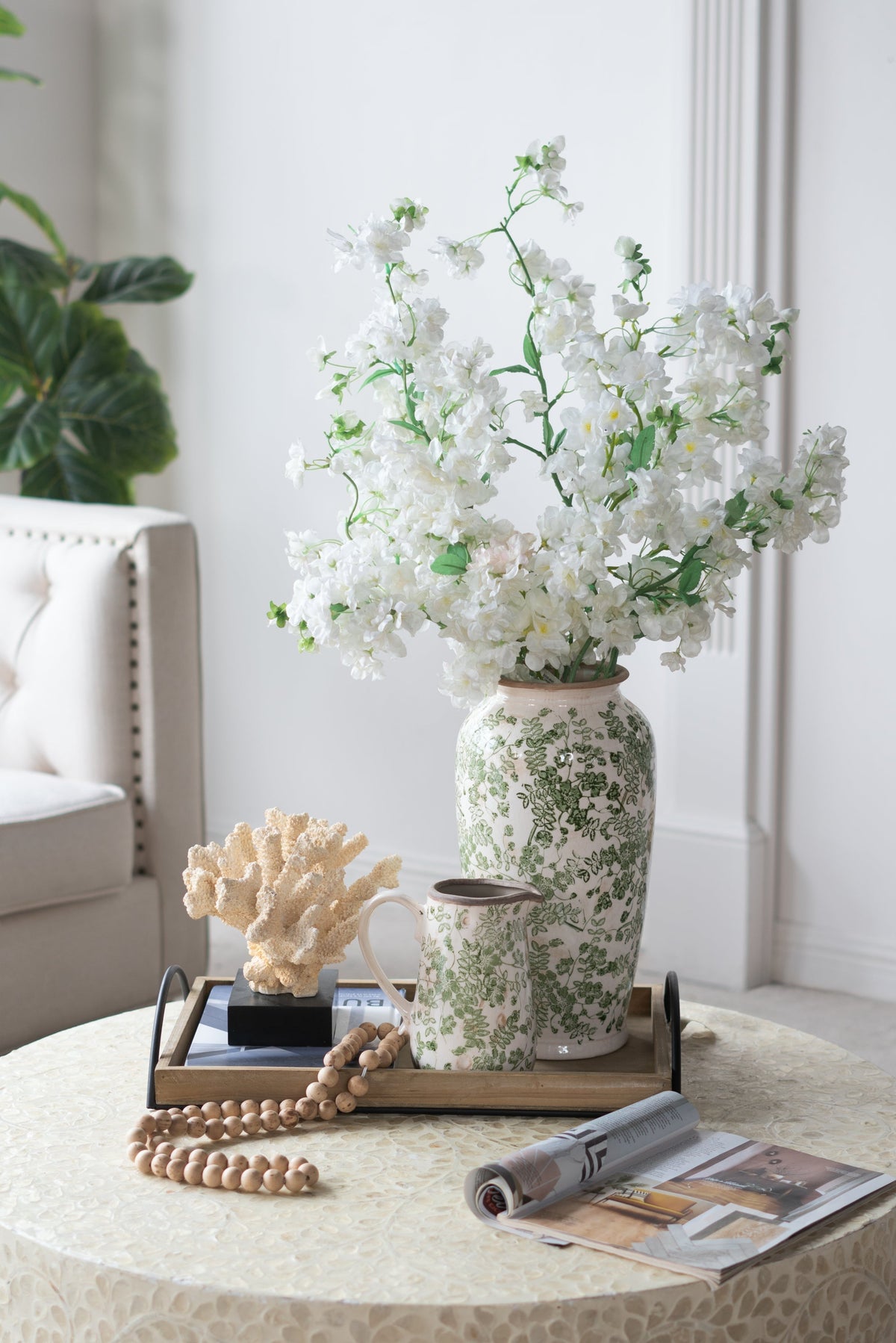 White ceramic flower vase with green floral pattern holding white blooms