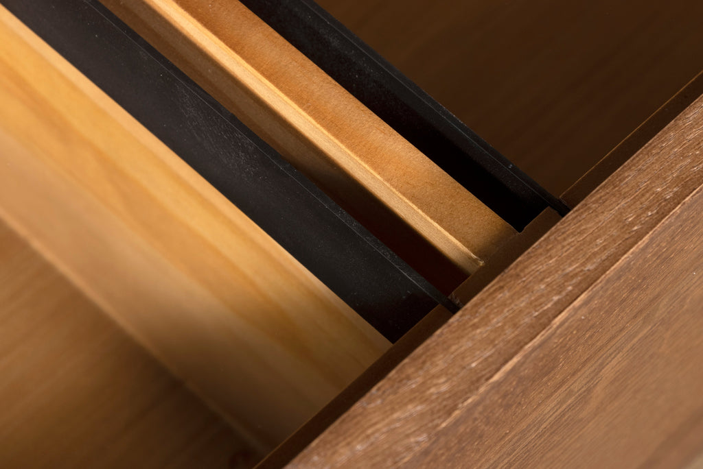 Close-up of drawer interior rails and dark drawer track on wood cabinet