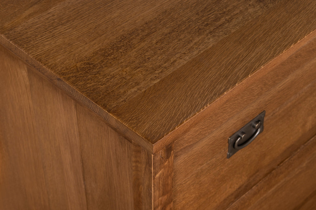 Close-up corner of walnut-stain cabinet with metal drawer pull
