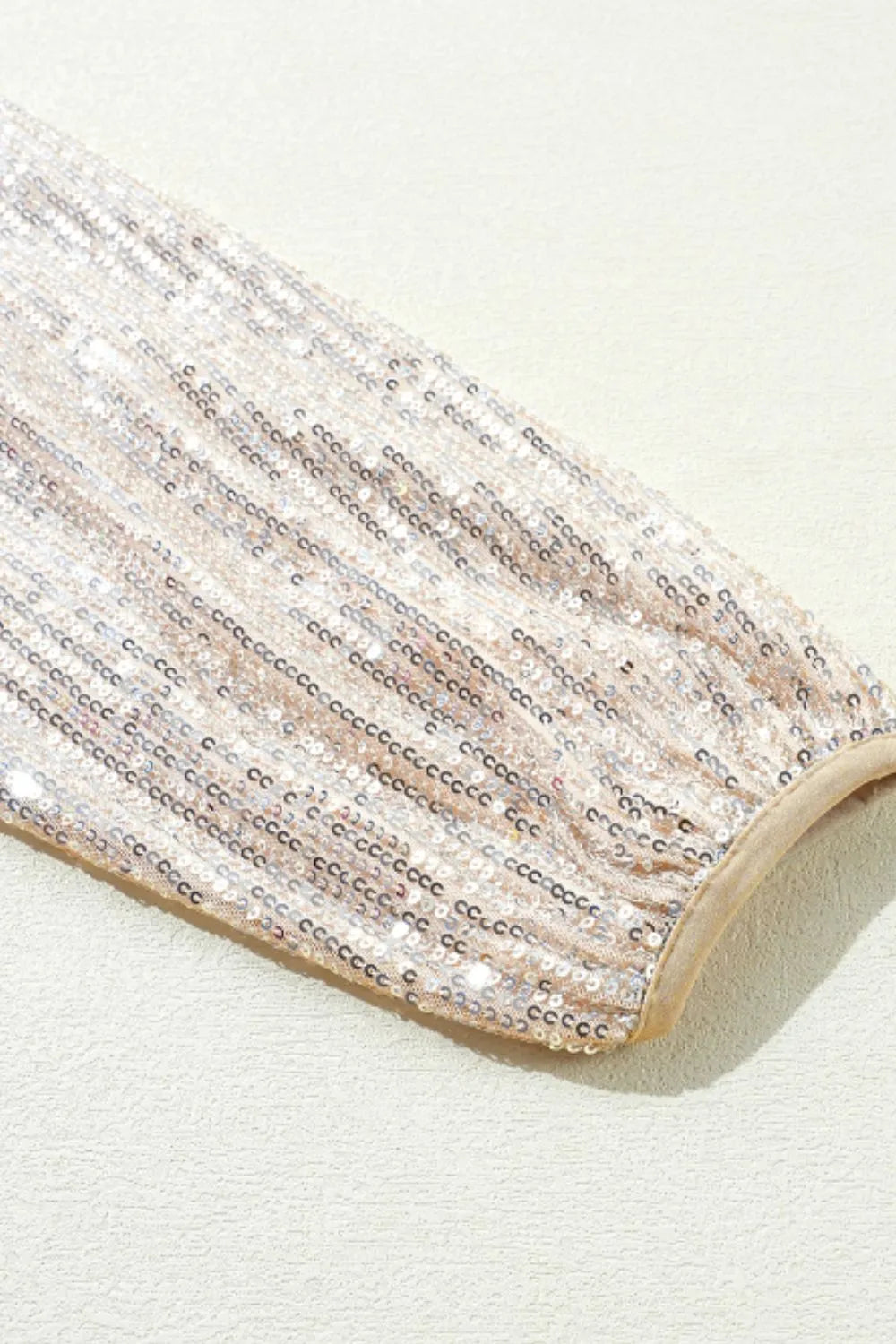 Close-up of cream sequin jacket hem with beige trim