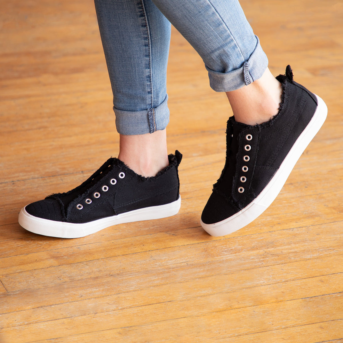 Black slip-on canvas sneakers with grommet eyelets and white sole