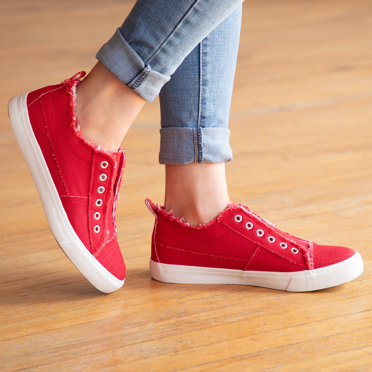 Red slip-on canvas sneakers with eyelet laces and white rubber sole