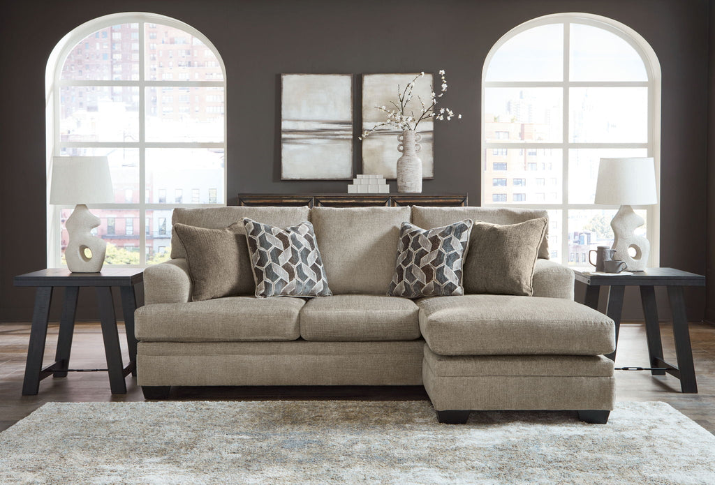 Upholstered sectional sofa with chaise, multiple patterned throw pillows and light beige fabric