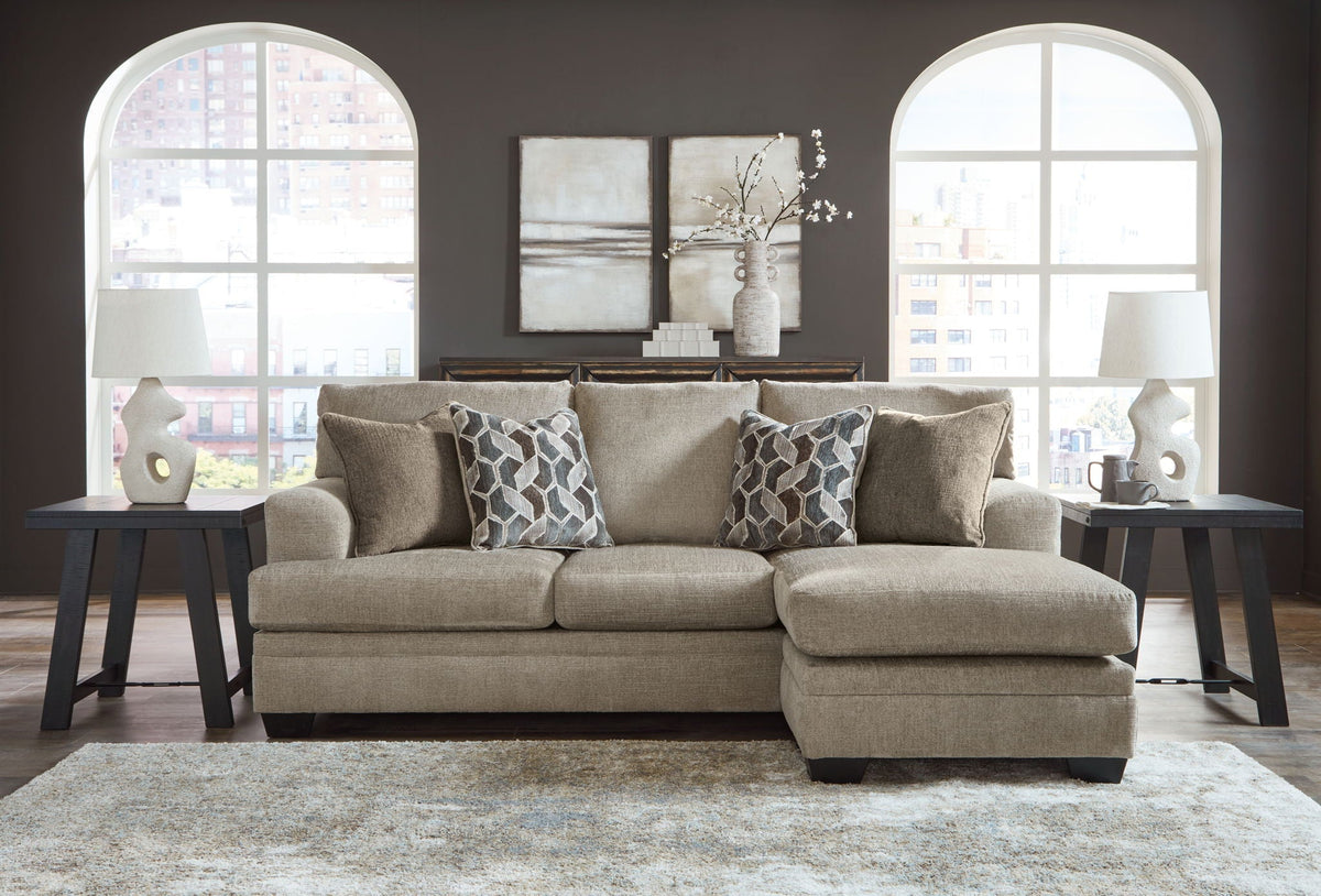 Upholstered sectional sofa with chaise, multiple patterned throw pillows and light beige fabric