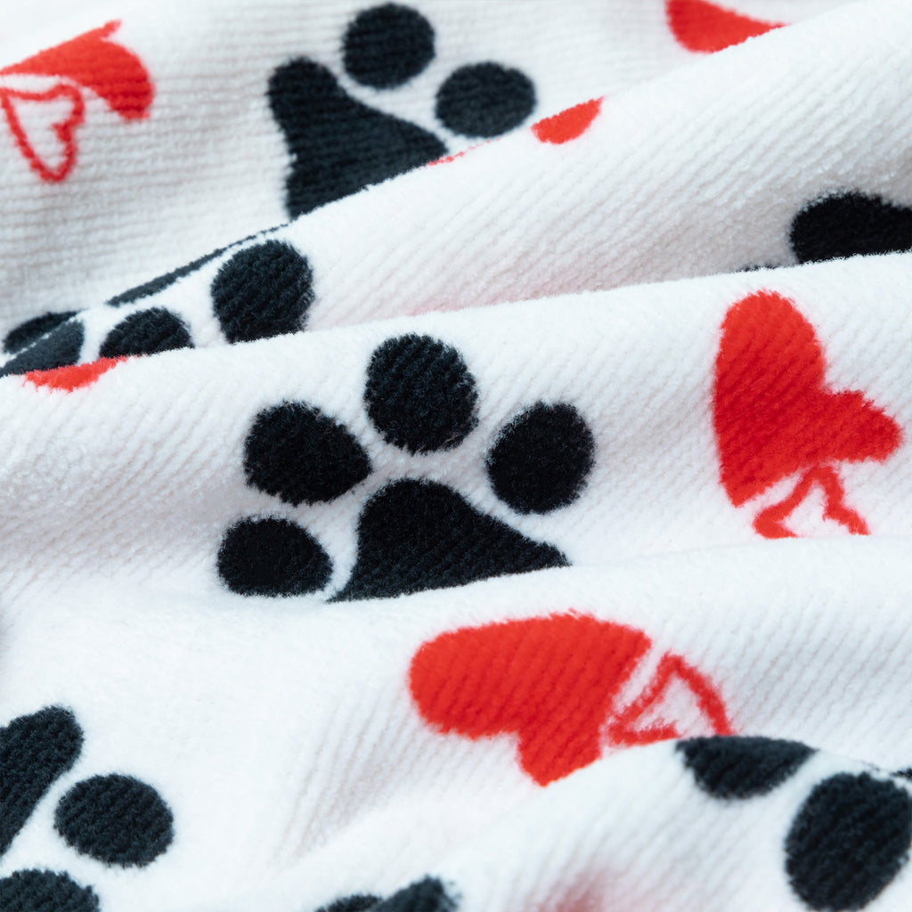 Close-up of white bath towel fabric with black paw prints and red heart pattern