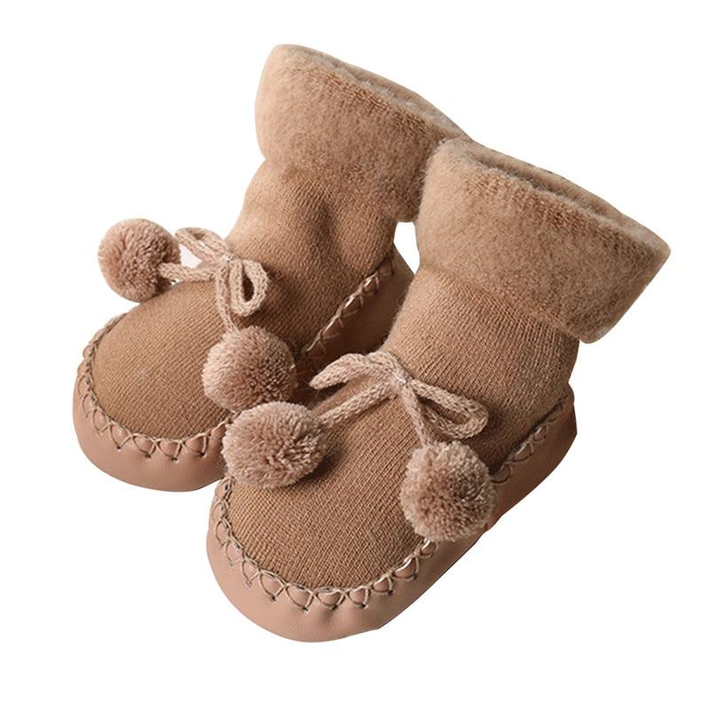 Pair of baby socks in coffee brown with pom-pom ties and stitched soles