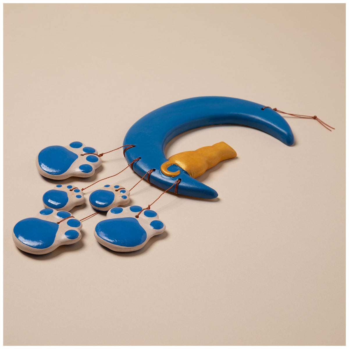 Ceramic crescent moon wind chime with blue paw charms and a gold cat figure on strings