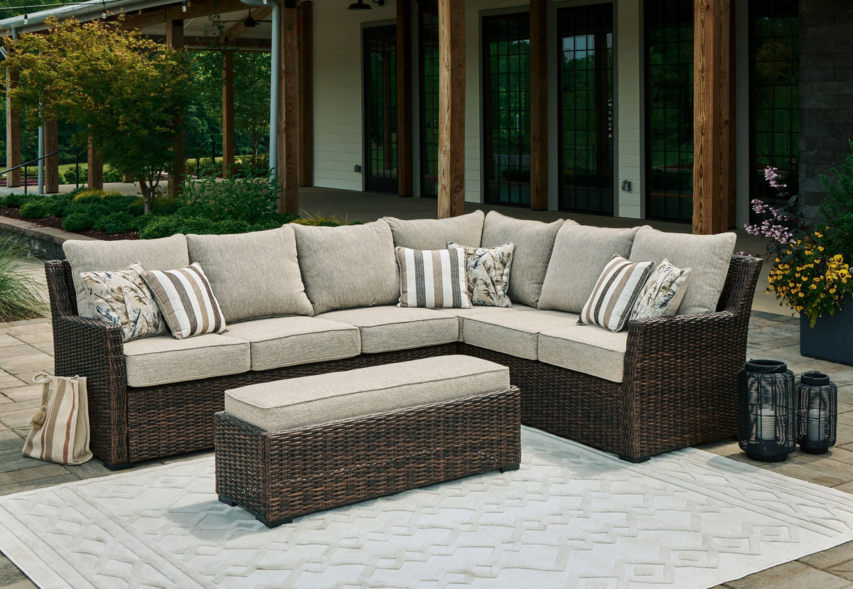 Sectional sofa set with brown wicker frame, light beige cushions and striped throw pillows