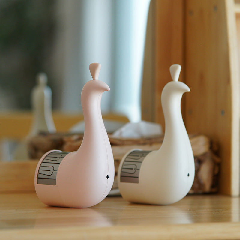 Pair of white peacock-shaped lamps on a wooden table