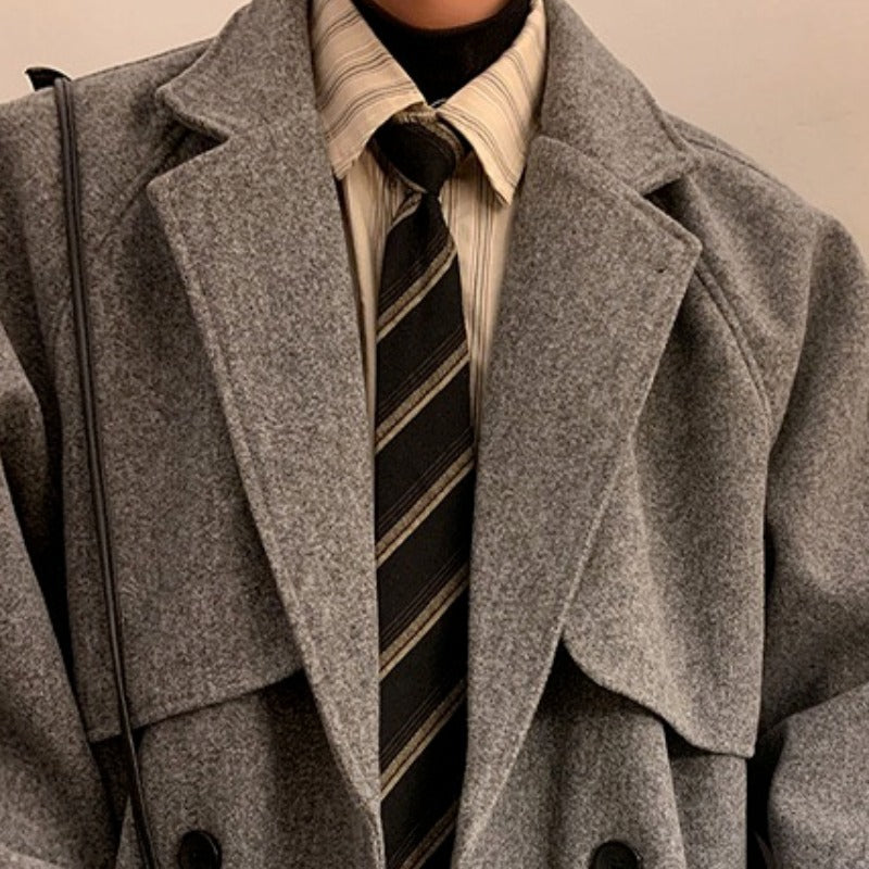 Gray wool overcoat close-up: wide lapels, double-breast buttons, and structured shoulder