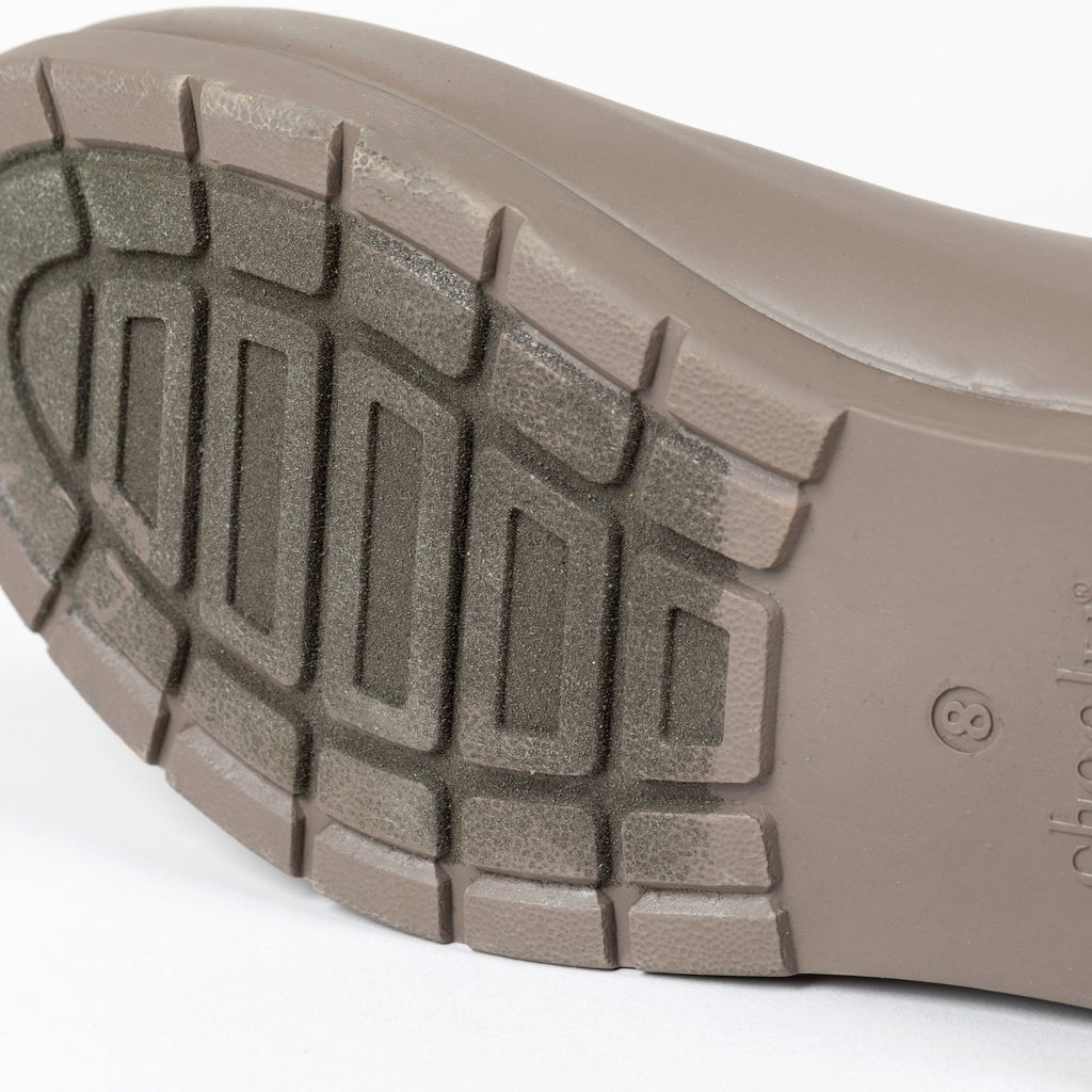 Taupe rain boot outsole with chunky tread pattern for traction.