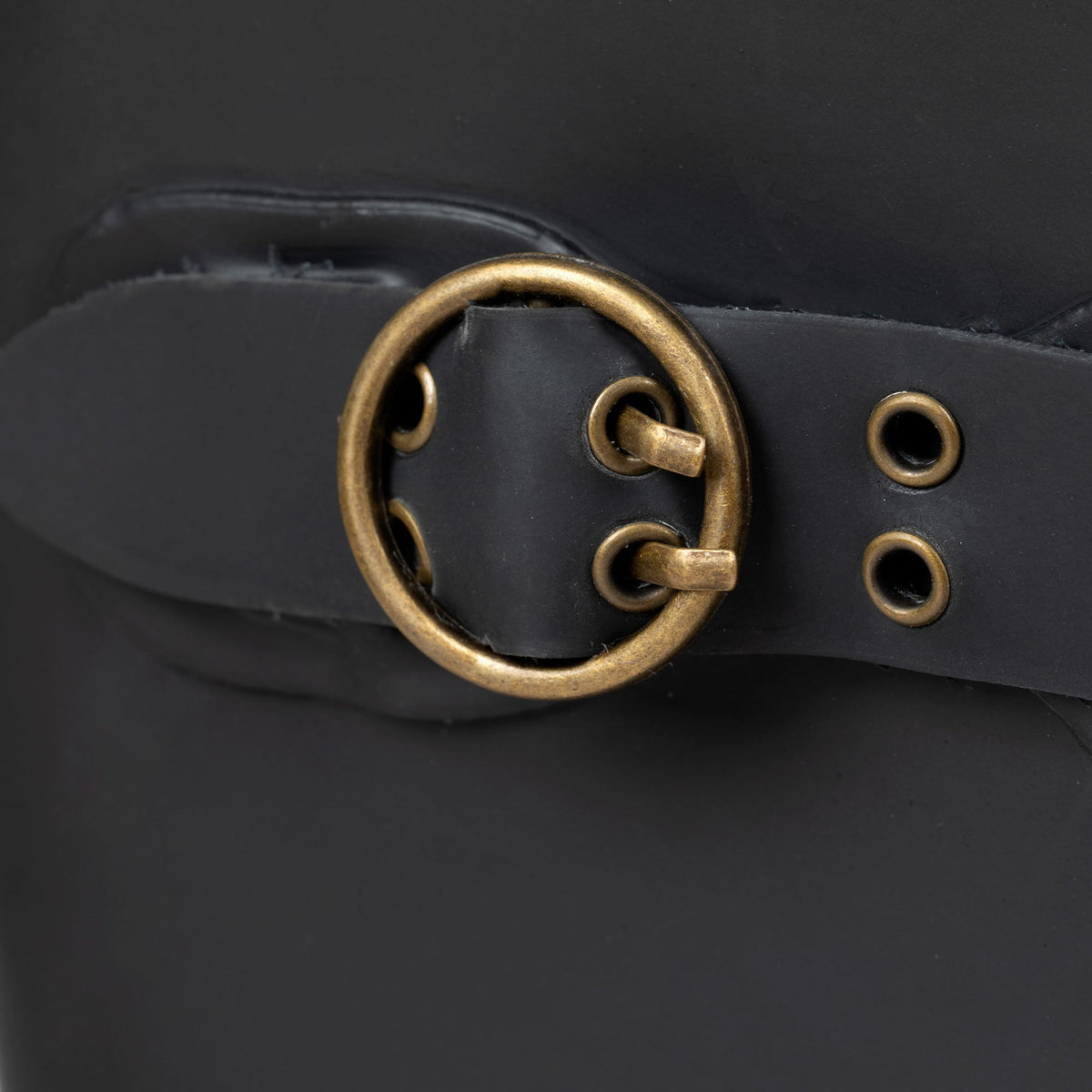 Close-up of black tall rain boot buckle strap with gold-tone ring and grommets.