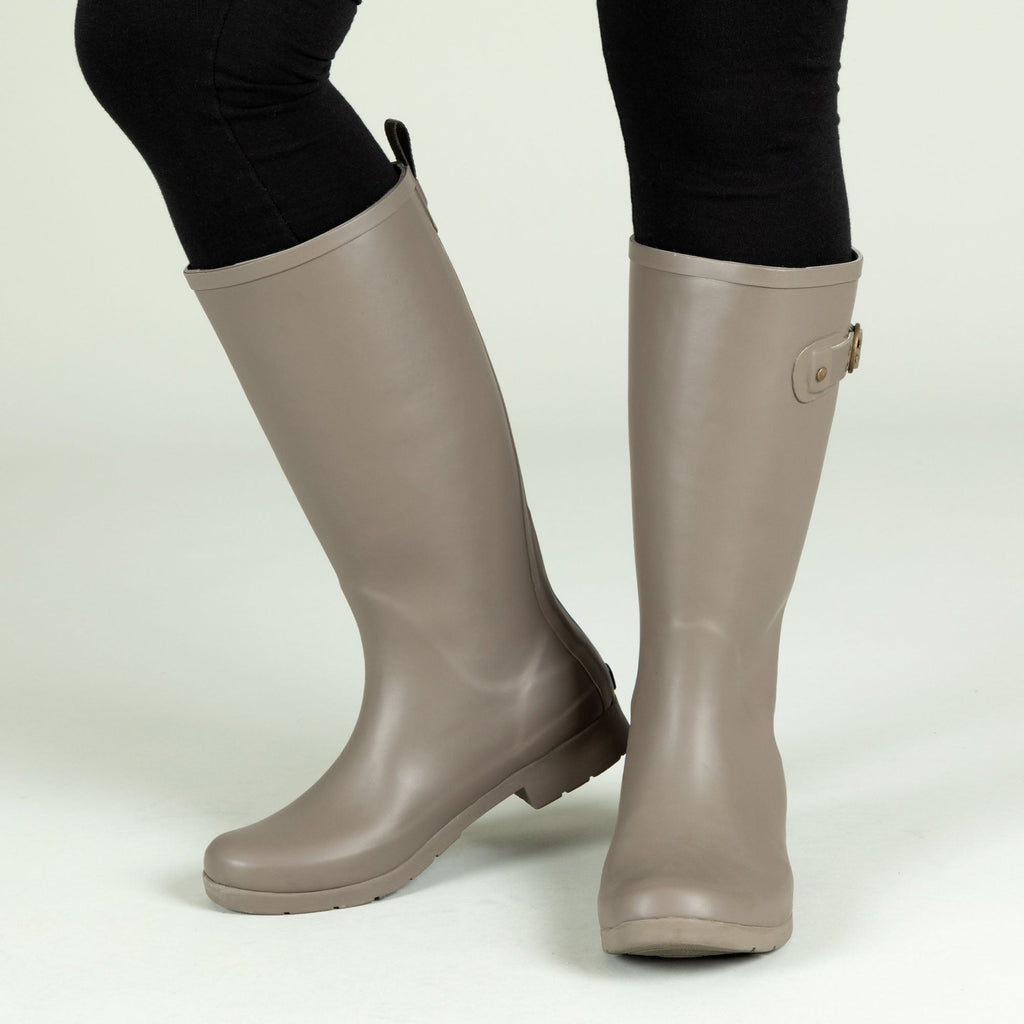 Taupe tall rain boots with side buckle strap and matte finish, knee-high style.