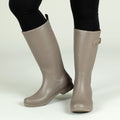 Taupe tall rain boots with side buckle strap and matte finish, knee-high style.