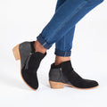 Black ankle boots with side zipper and tassel tie pull, styled with blue jeans.