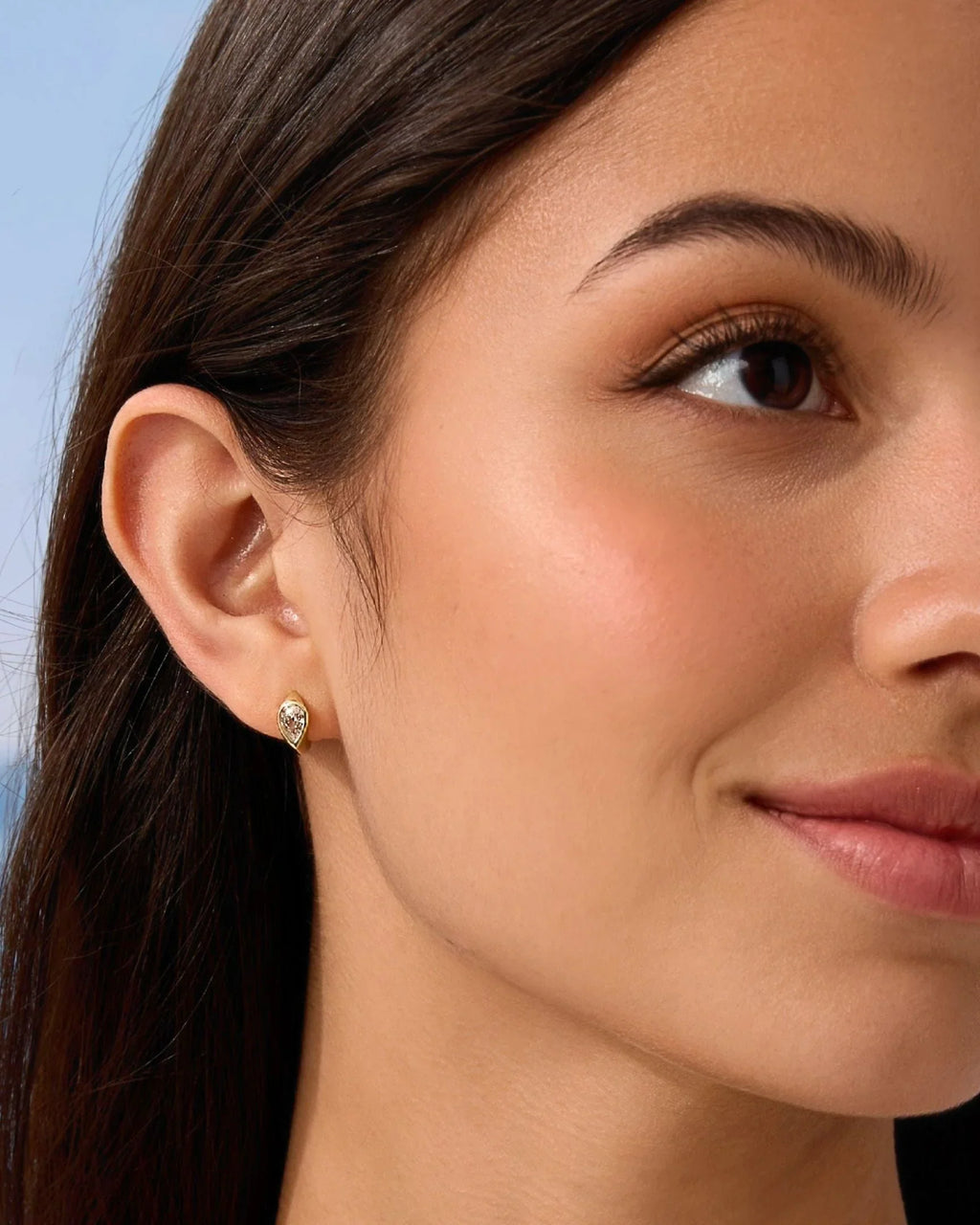 Gold small hoop earrings with clear stone detail, close-up on ear
