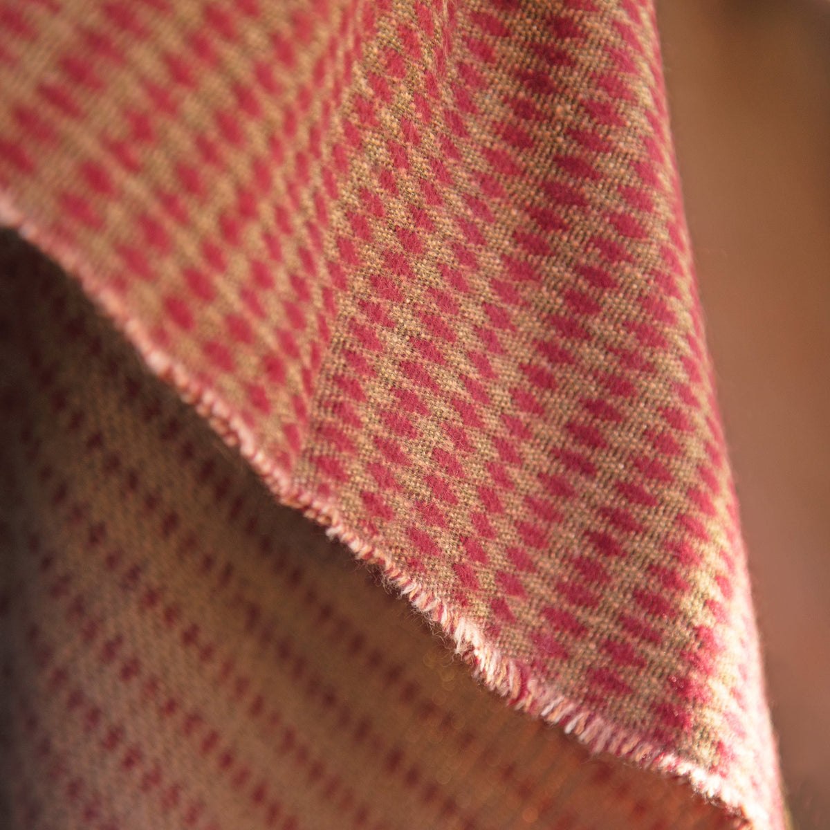 Close-up of khaki and red striped woven poncho fabric with edge fringe