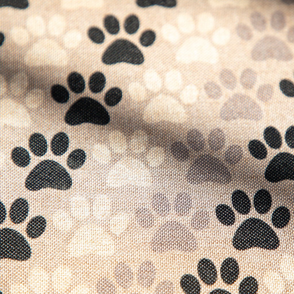 Close-up of tan fabric with repeating black paw print icons