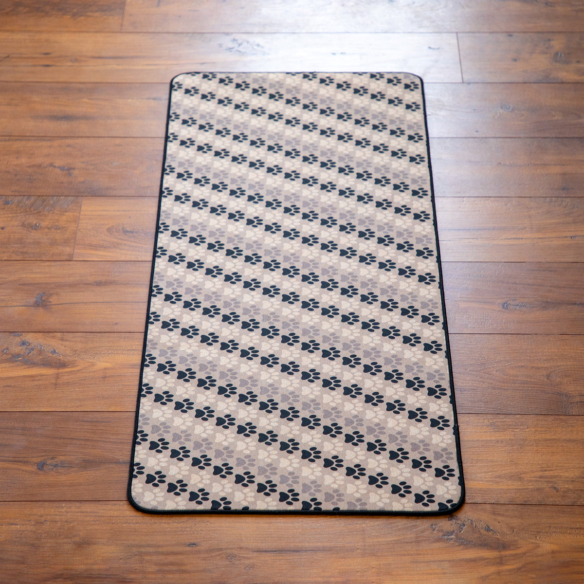Tan floor runner featuring repeating black paw prints and a dark outline border