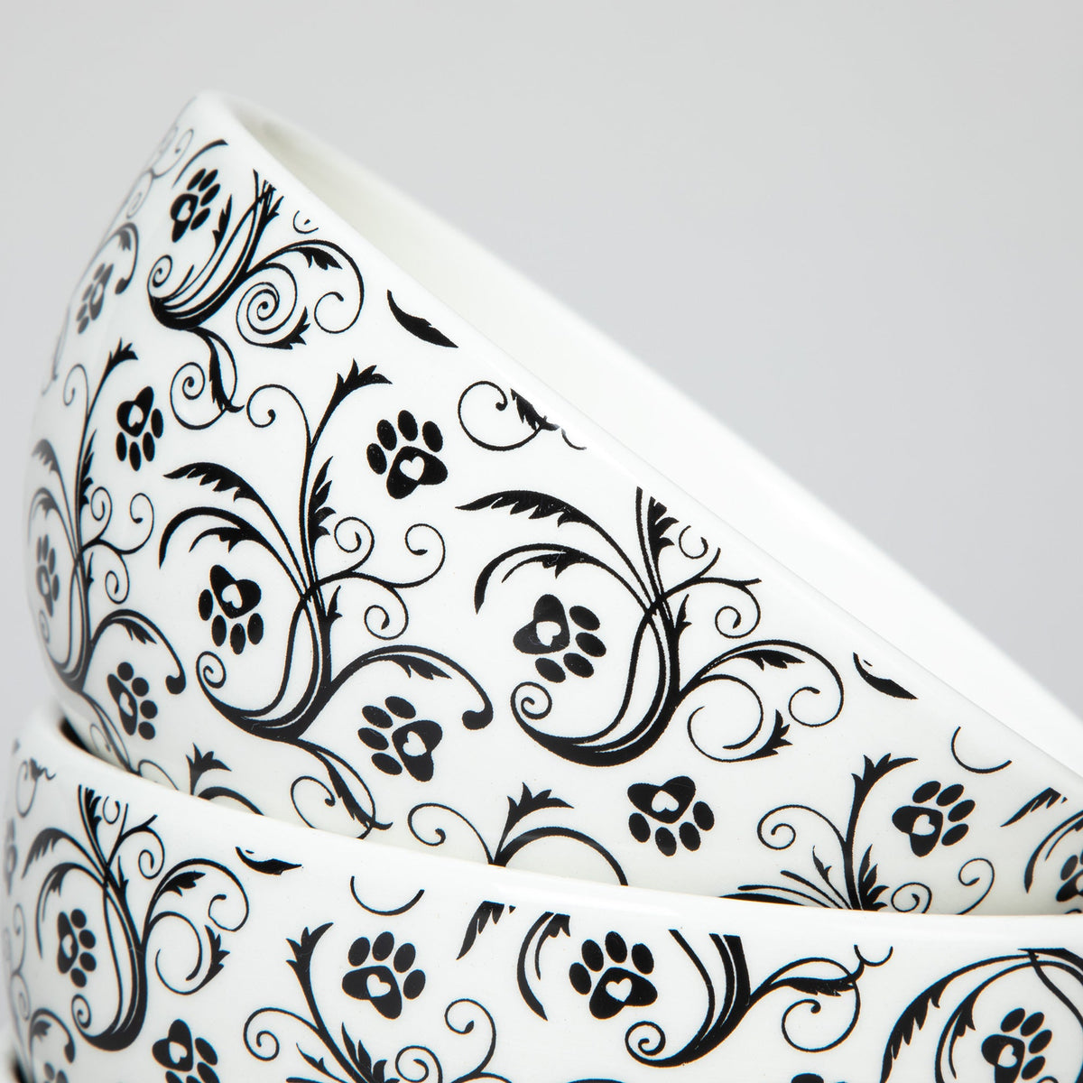 Close-up of ceramic bowl with black paw-and-swirls pattern on white surface