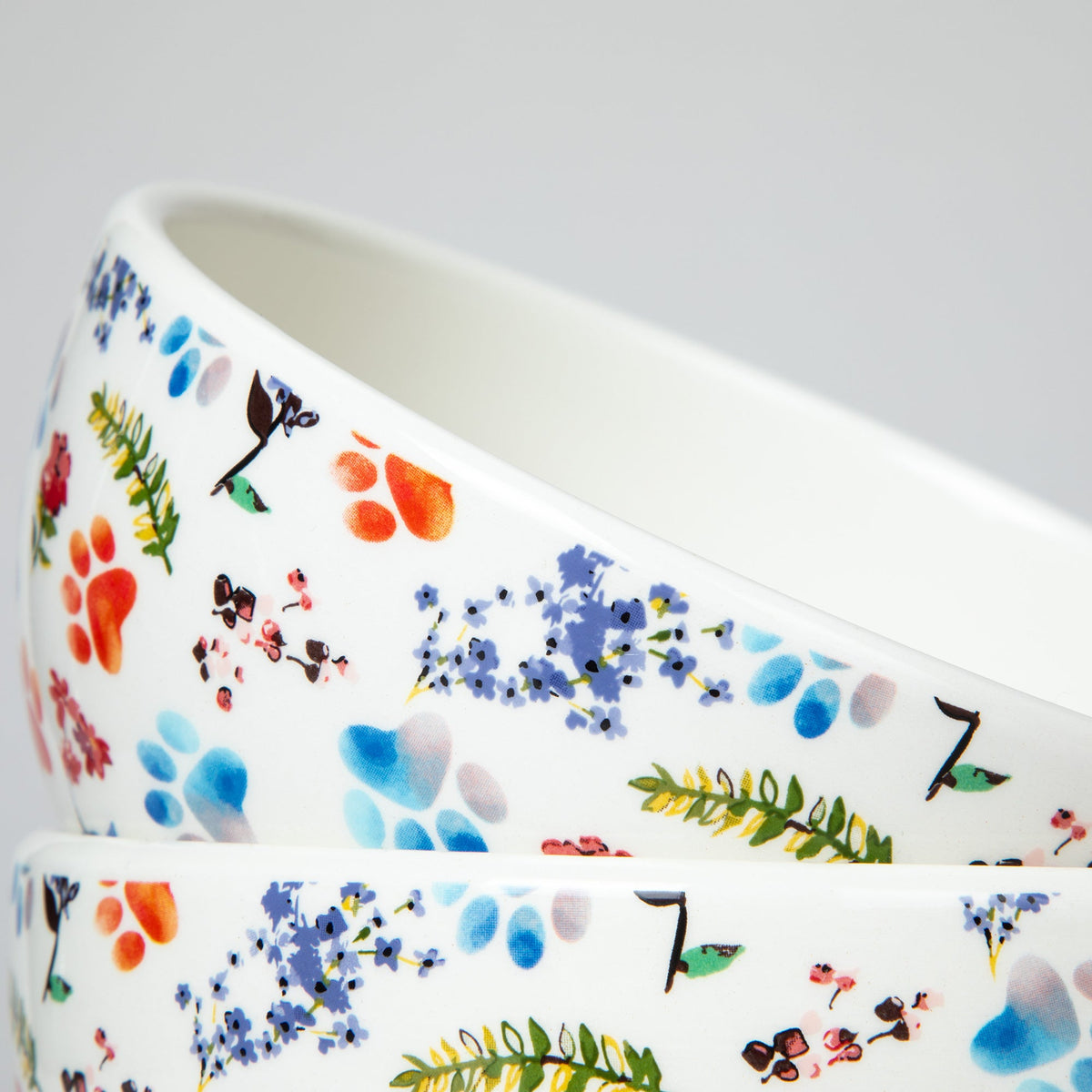 Ceramic bowl close-up with multicolor paw prints, flowers, and paw-swirl accents