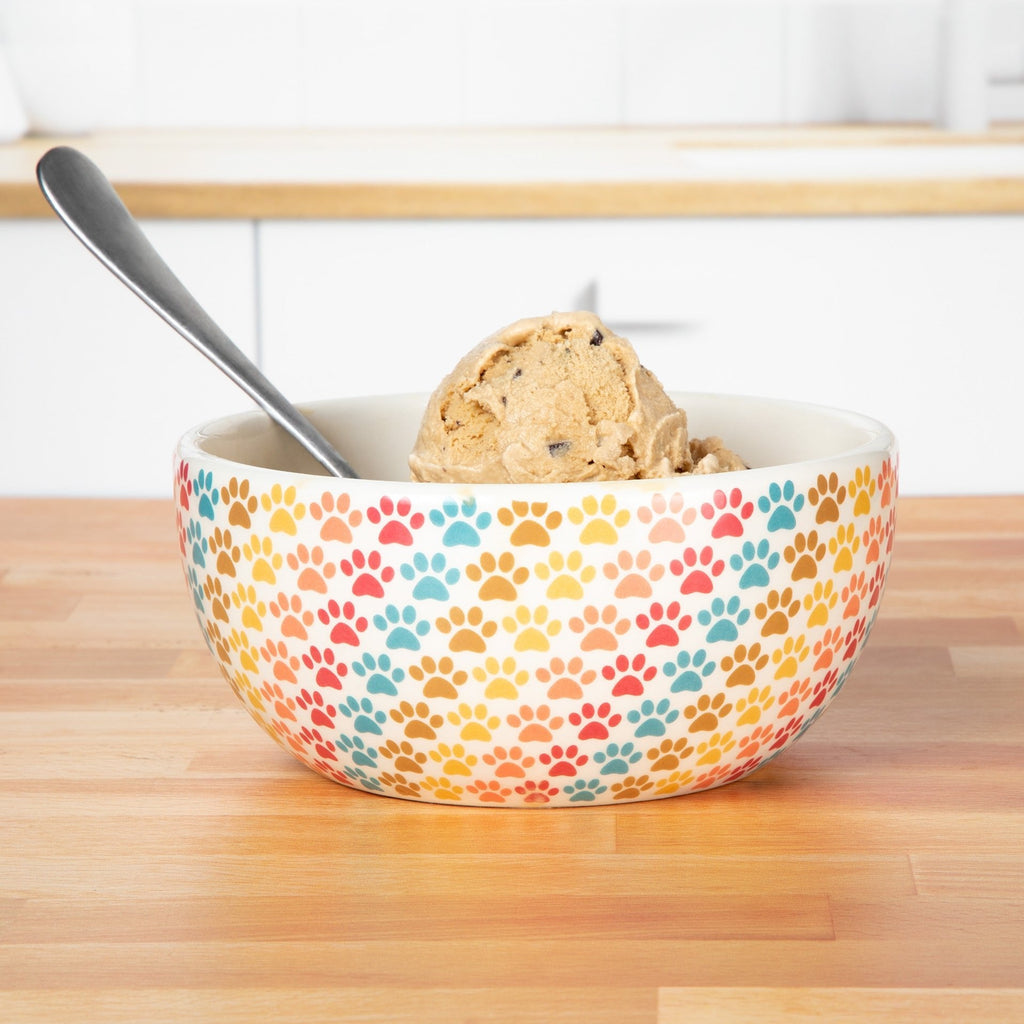 Ceramic pastel paw-print soup bowl with spoon and food inside, white interior