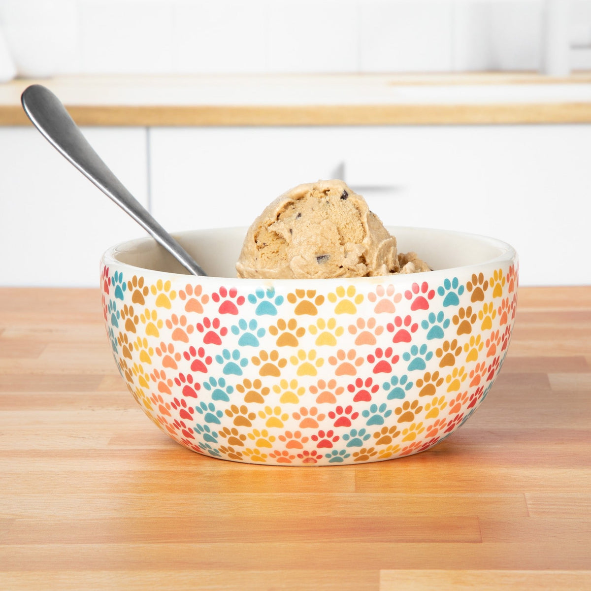 Ceramic pastel paw-print soup bowl with spoon and food inside, white interior