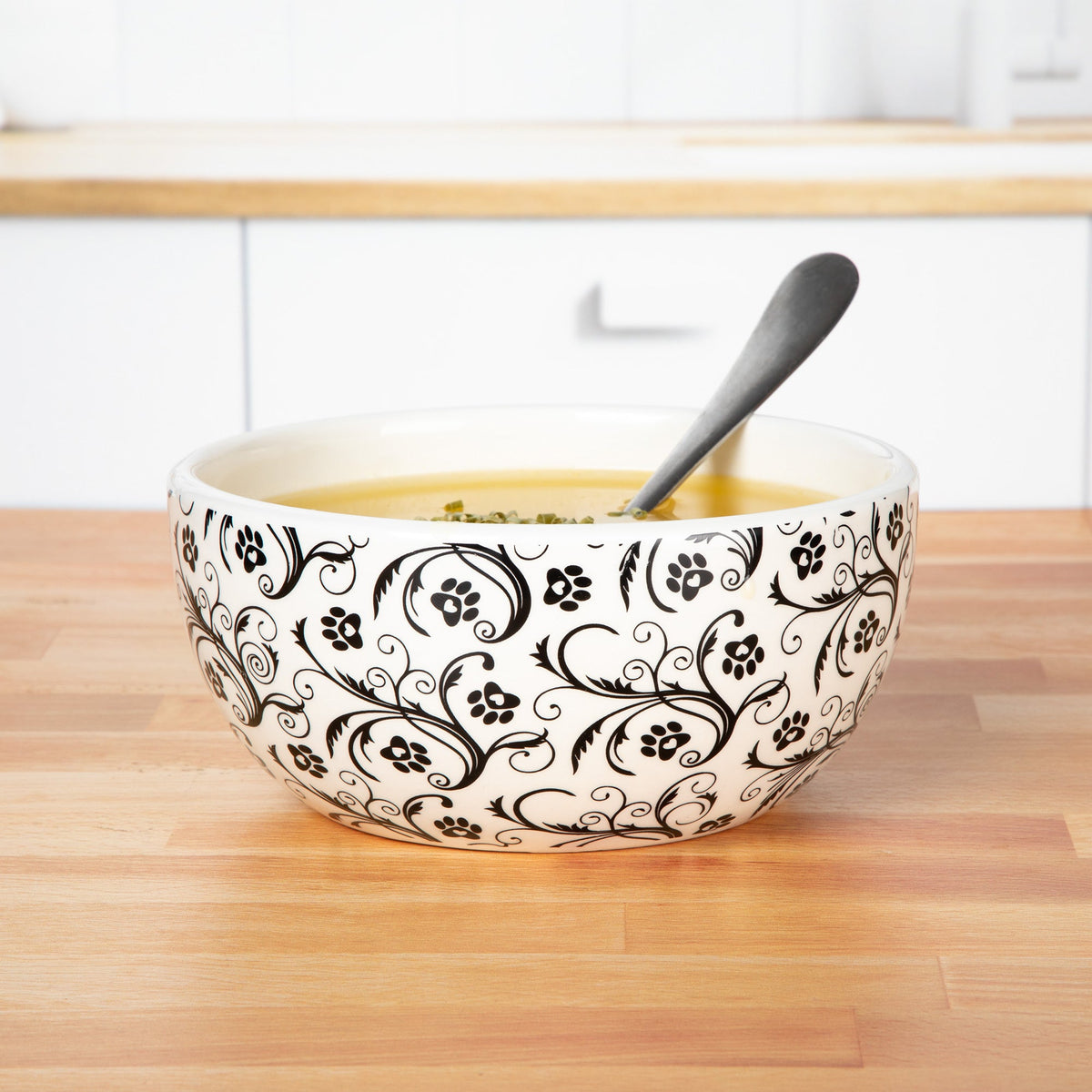 Ceramic black-and-white swirl paw bowl with spoon and food, white interior