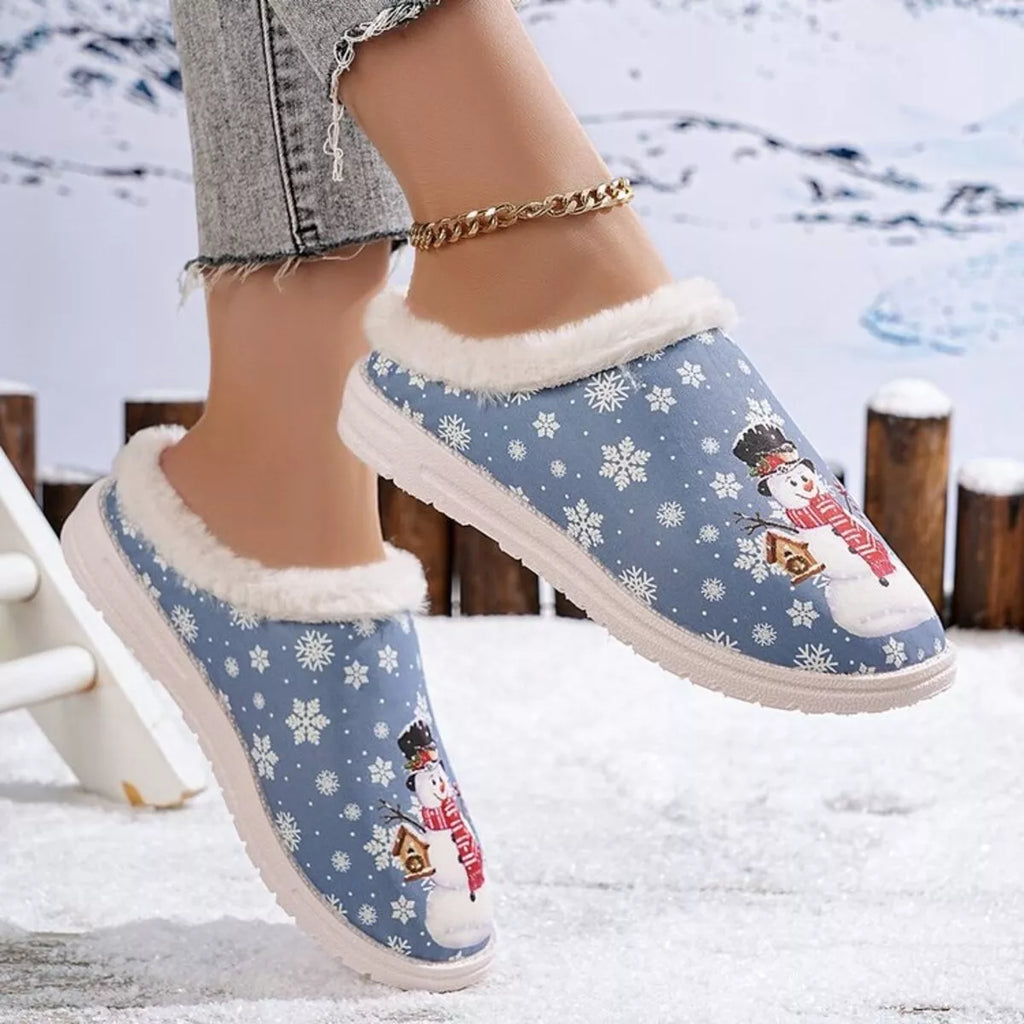 Blue plush-lined Christmas slippers with snowman and nutcracker graphics, low profile sole