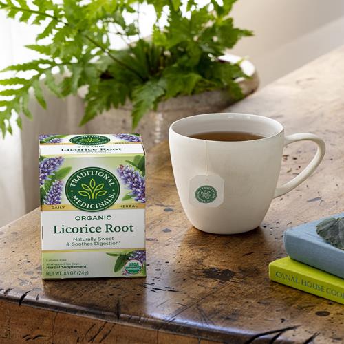 Organic licorice root herbal tea box beside a white mug of tea
