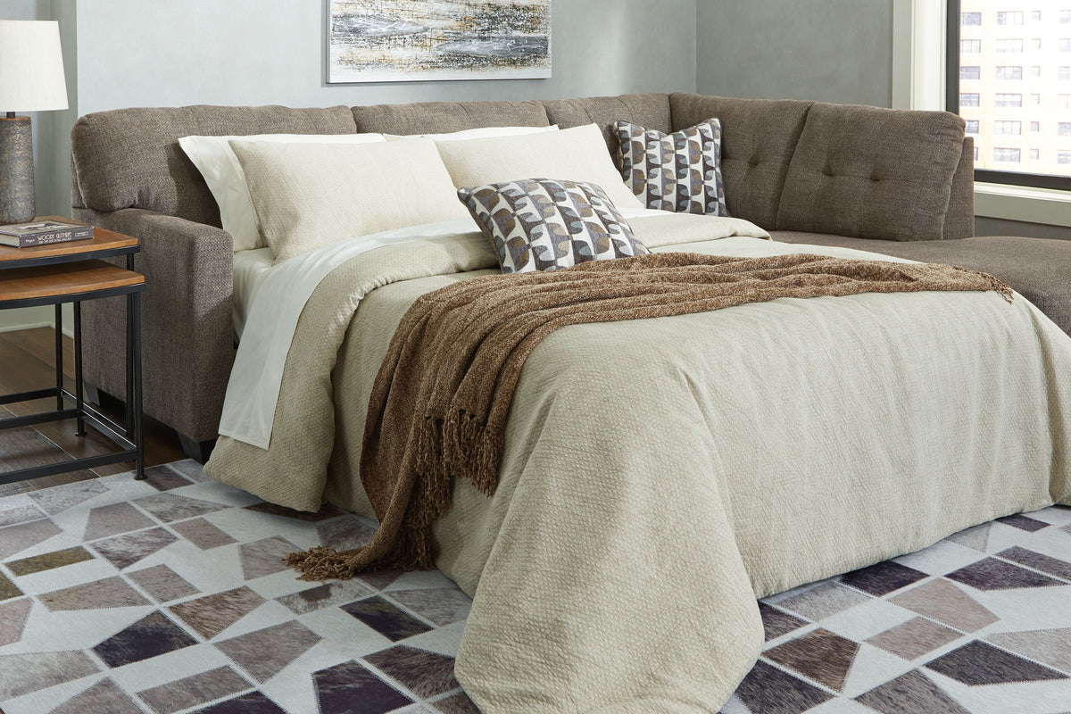 Light gray chaise sleeper sectional with tufted back, arm chaise and draped blankets