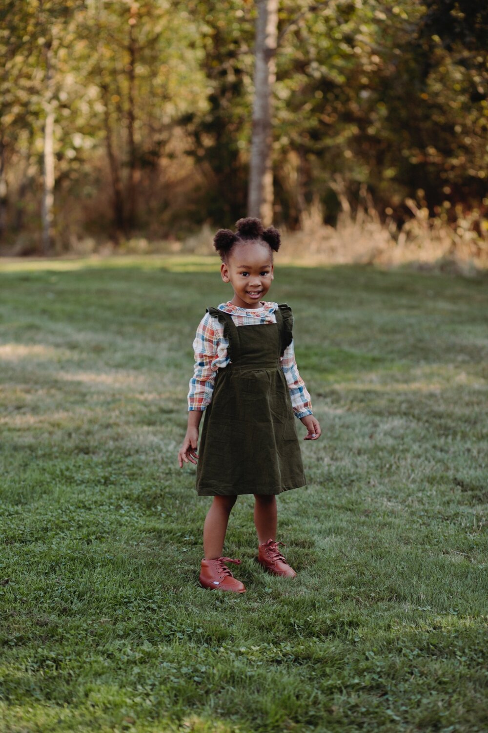 Brown lace-up toddler shoes worn on green grass