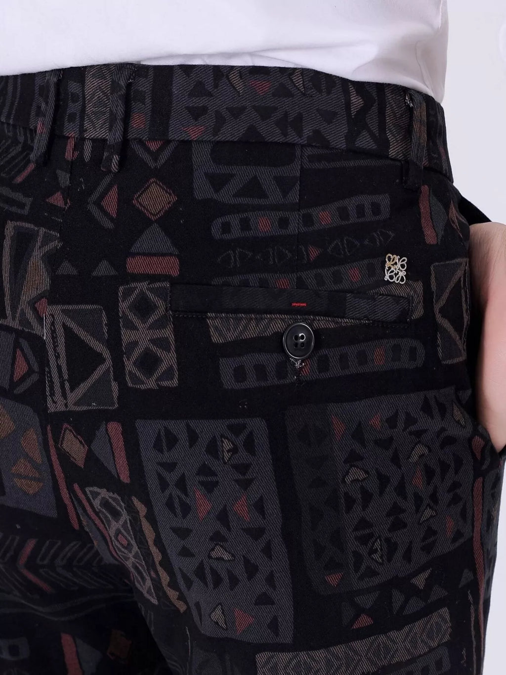 Close-up of men's black printed casual pants: button front and side pocket detail