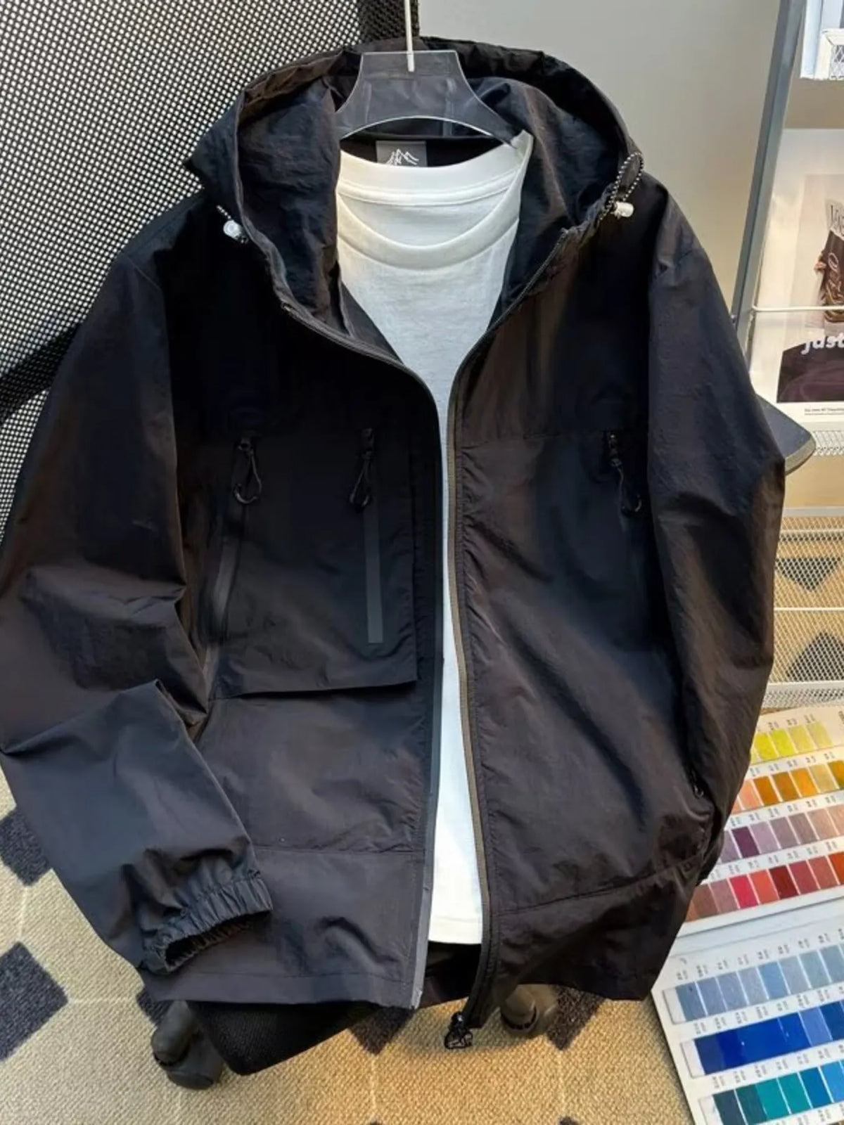Lightweight hooded windbreaker jacket in black with full zip and flap pockets