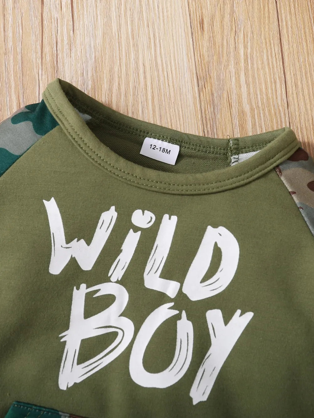 Kids’ army green top with “Wild Boy” text print and camouflage sleeve detail