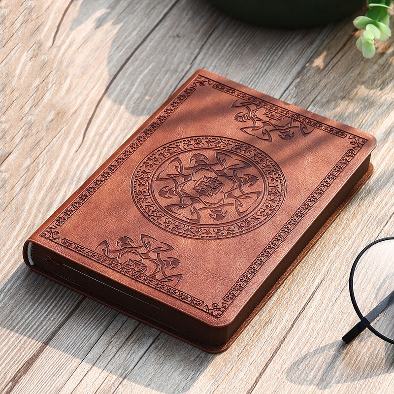 A6 leather mini notebook with embossed emblem on brownish-red cover