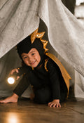 Black and gold dragon costume with hood, spikes on headpiece, and wing cape