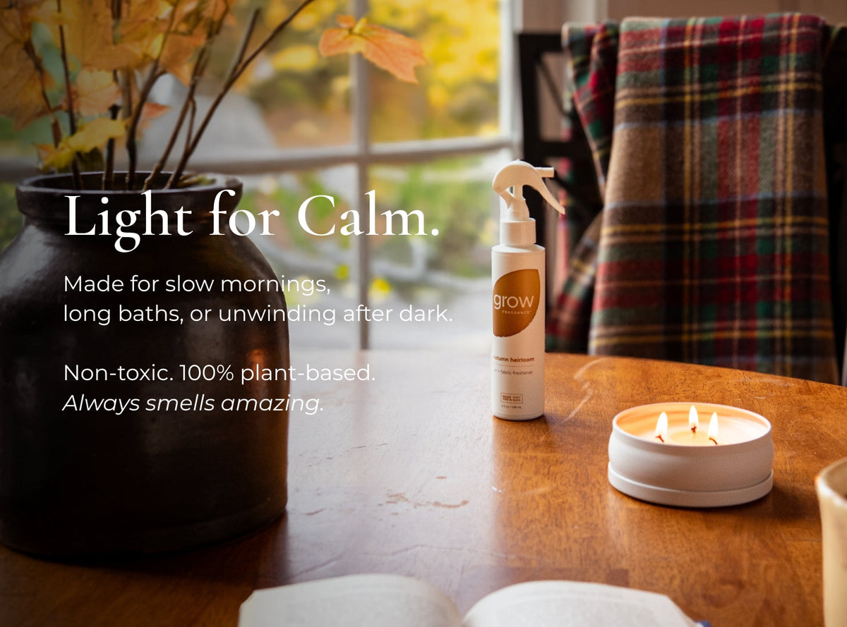Lit white 3-wick candle in a round tin on a table, with three flames