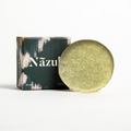 Green shampoo bar in a round shape with a cardboard box behind it
