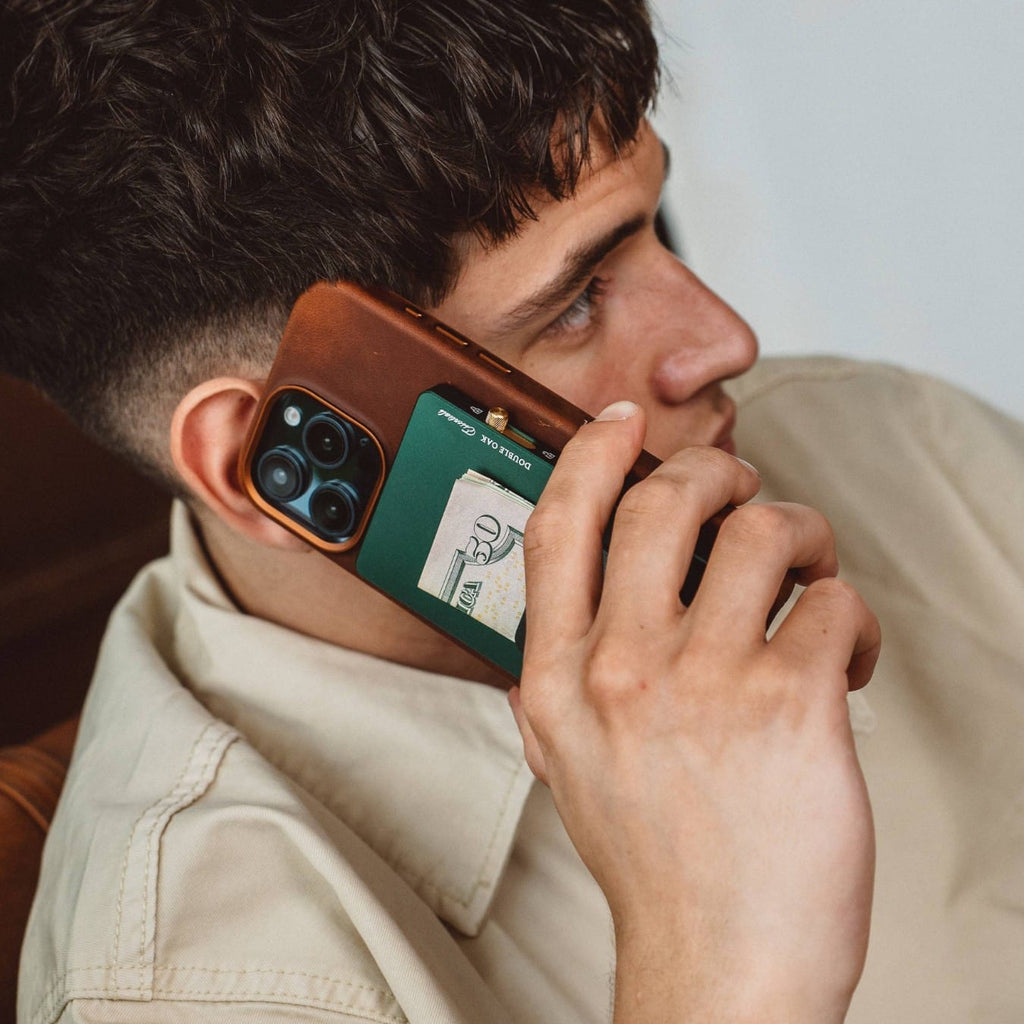 Teal pop-up cardholder with a card slid out, held near a brown smartphone