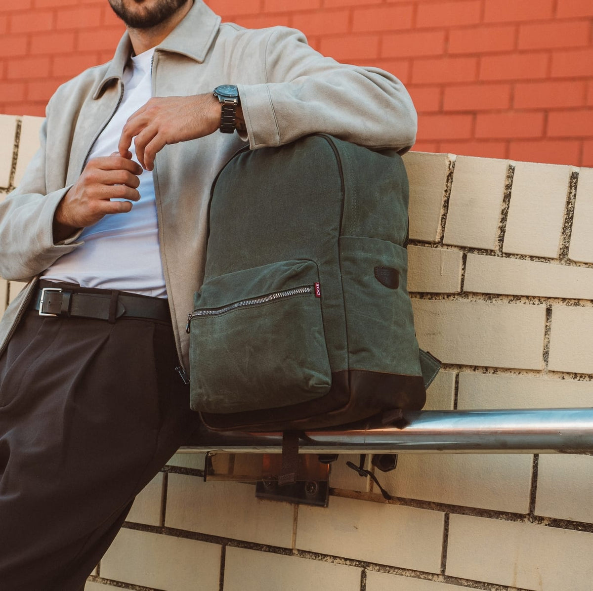 Olive green backpack with front zip pouch and leather-look top straps