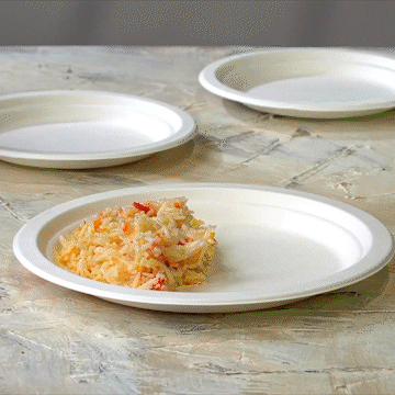 Multiple 9-inch white disposable sugarcane paper plates with food portions