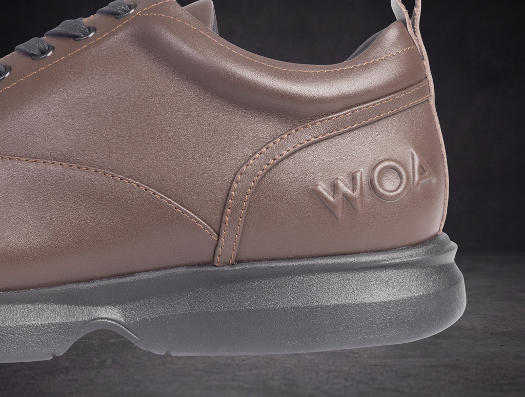 Taupe WOA sneaker side panel with embossed WOA logo and contrast stitching