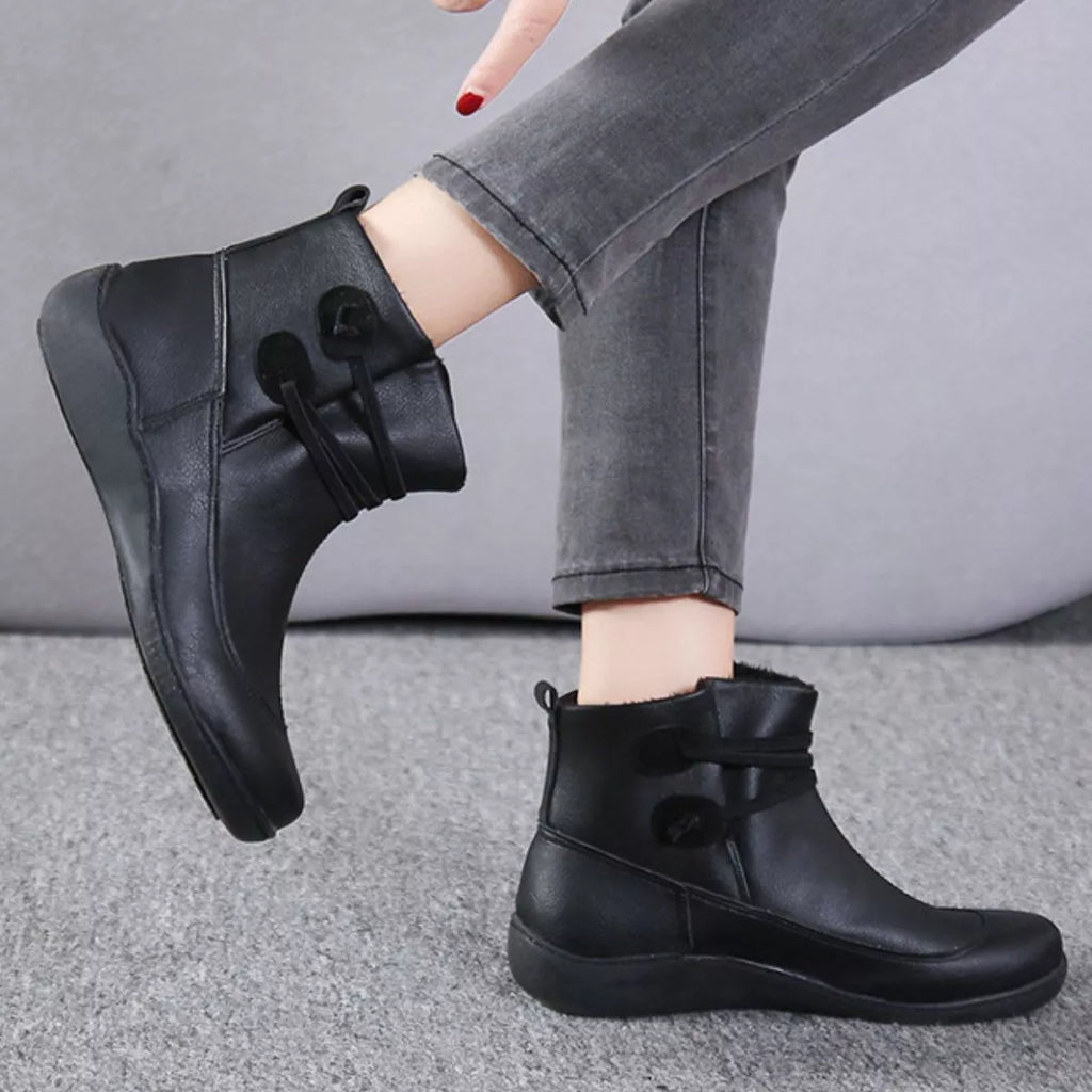 Button-detail ankle boots in black, slip-on style with side straps and low sole.