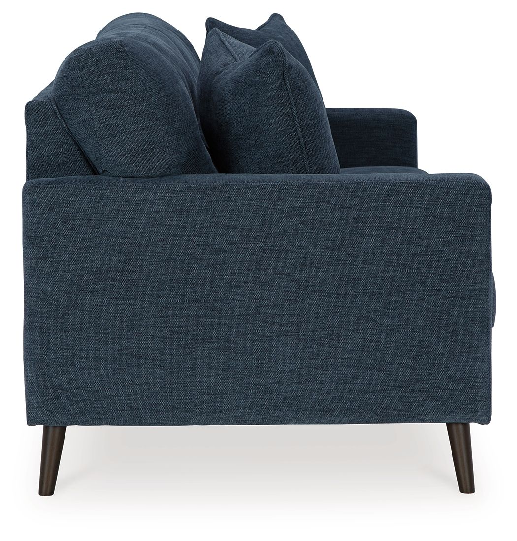 Blue upholstered sofa from side angle with back cushions and tufted seat backs