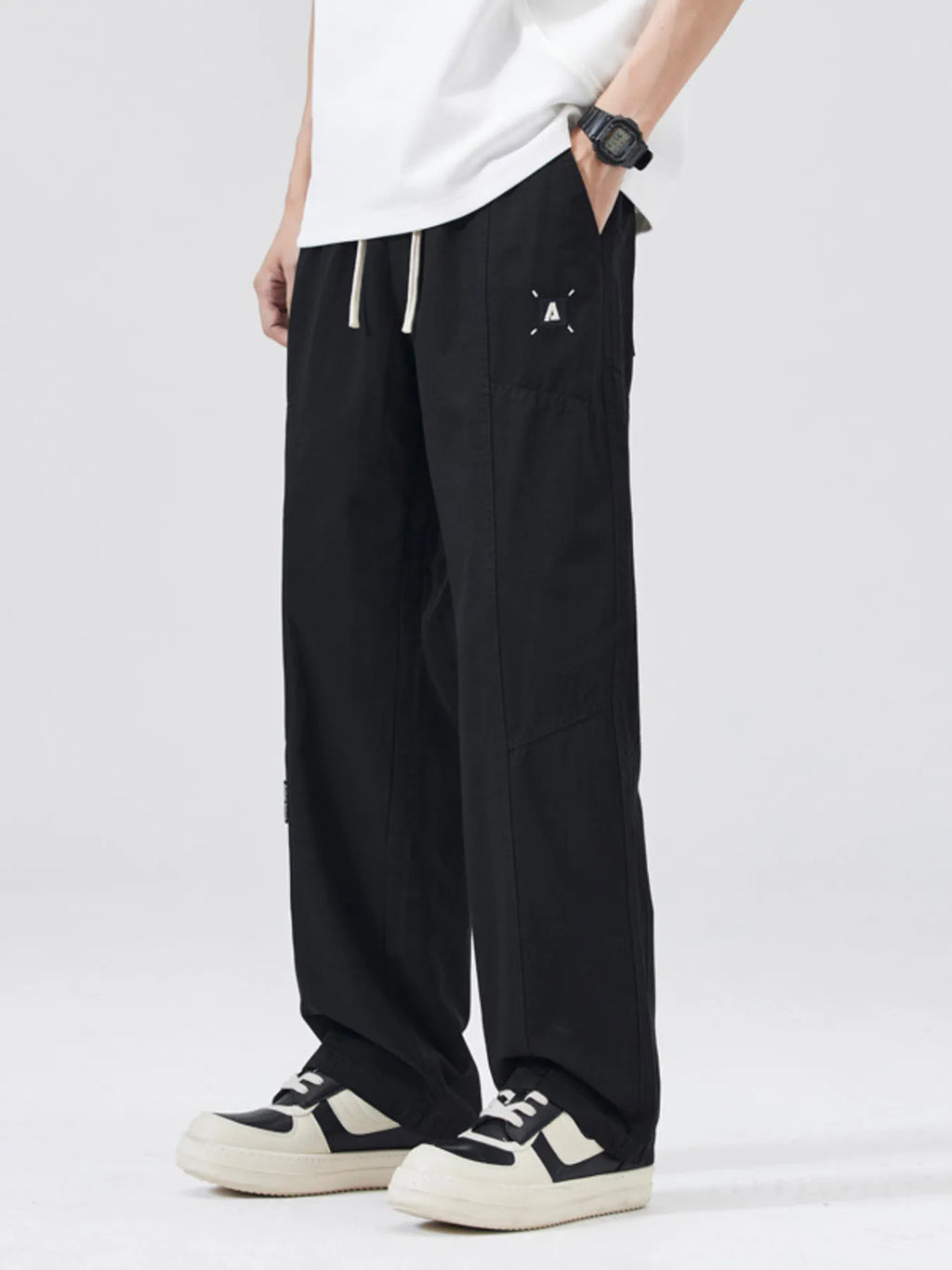 Black loose-fit drawstring pants with thigh logo patch and side pockets