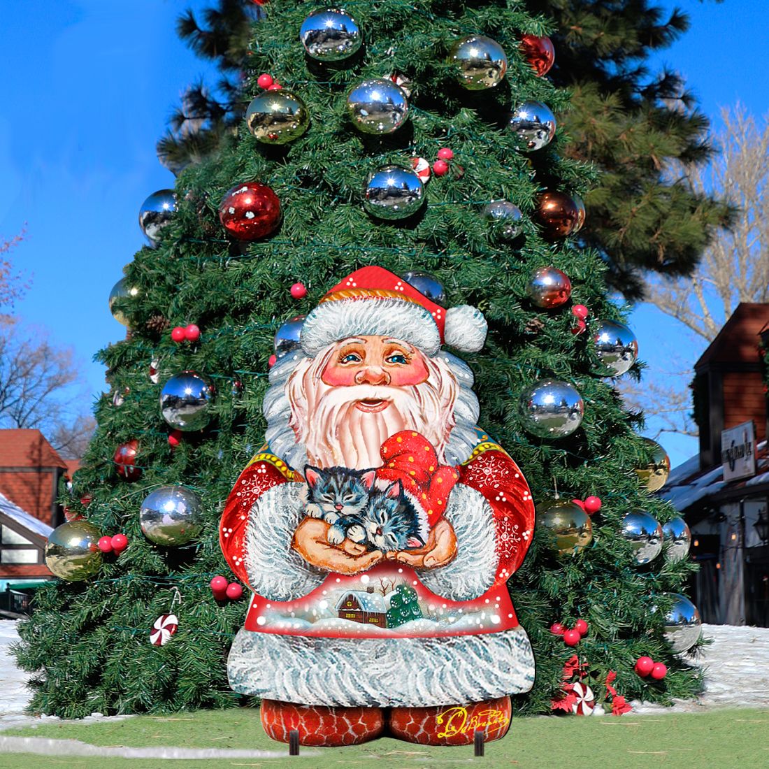 Santa holding a kitten yard sign centered in front of a decorated Christmas tree