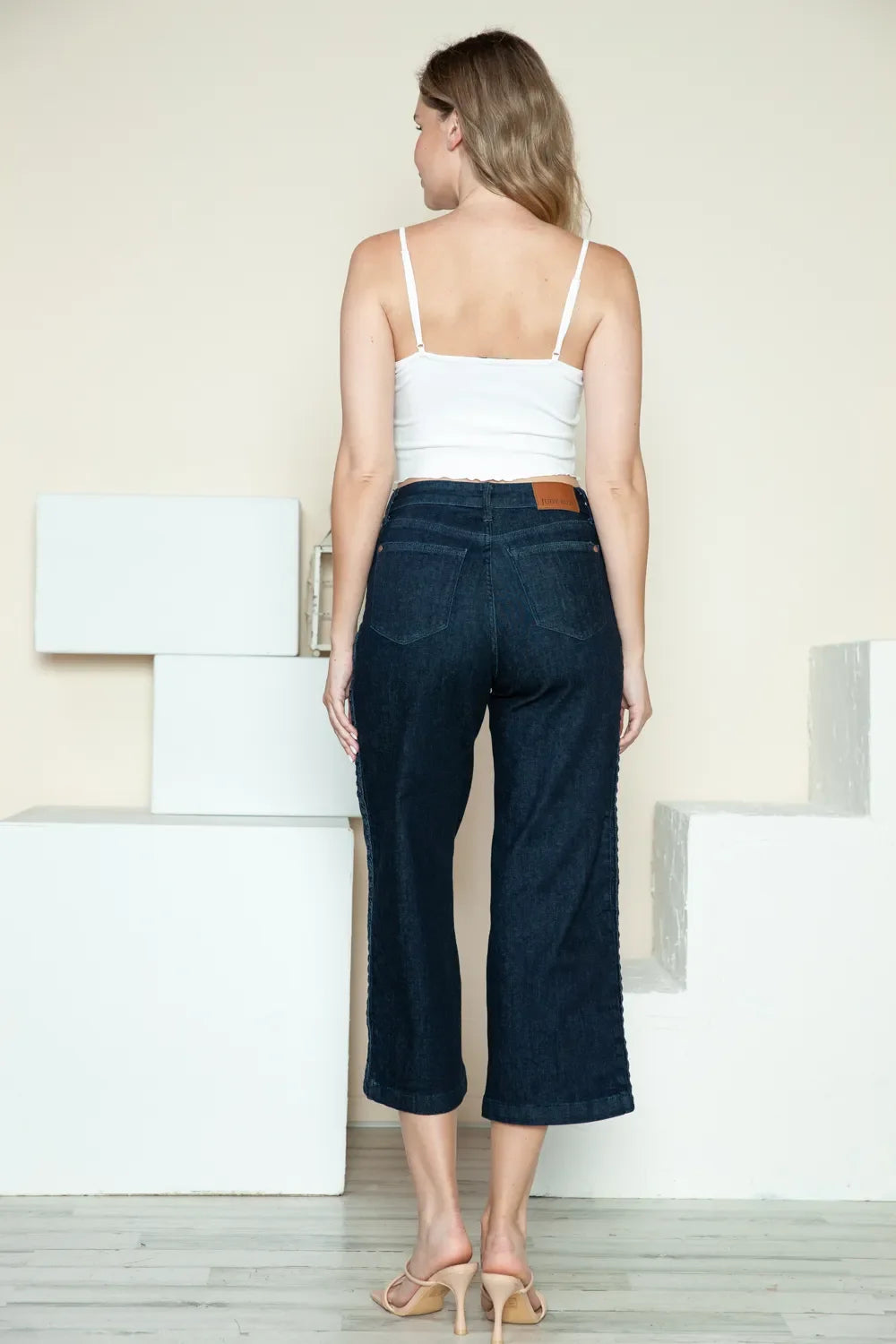 Dark wide-leg cropped jeans with side braid detail, rear three-quarter view
